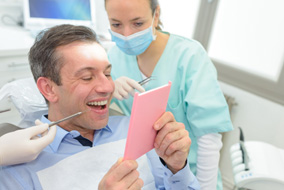 A patient looking in the mirror at his new dental crown