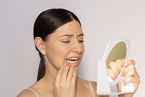 Concerned woman looking at her gums in mirror