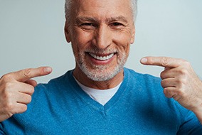 A handsome older man pointing to his dentures