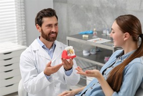 a dentist showing a patient a model of an implant crown