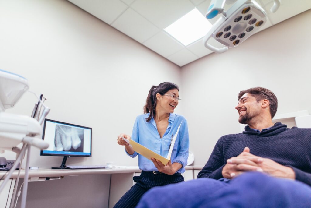 Smiling dentist talking to patient during exam